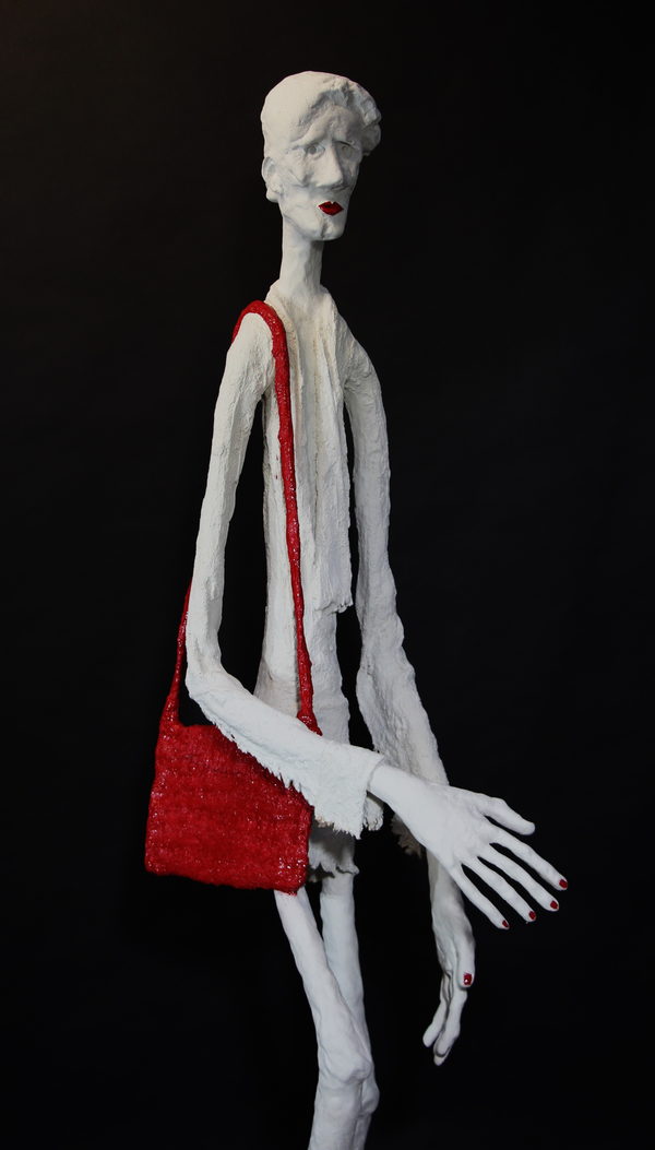 Closer view of the pale figure's head, hands and red shoulder bag.