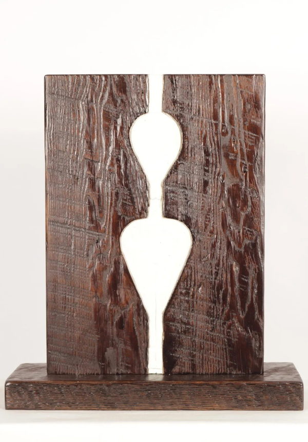 Frontal view of the dark wooden composition with two white tapering forms aligned vertically above a rectangular base.