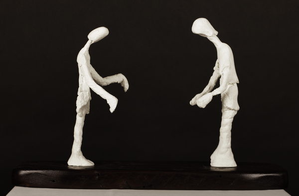 Two pale figures face one another on a shared dark, horizontal base.