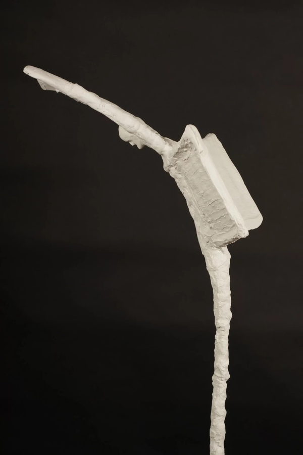 The Scribe by Valeriu Cazacevschi. Side view of the raised arms, open book and narrow body.