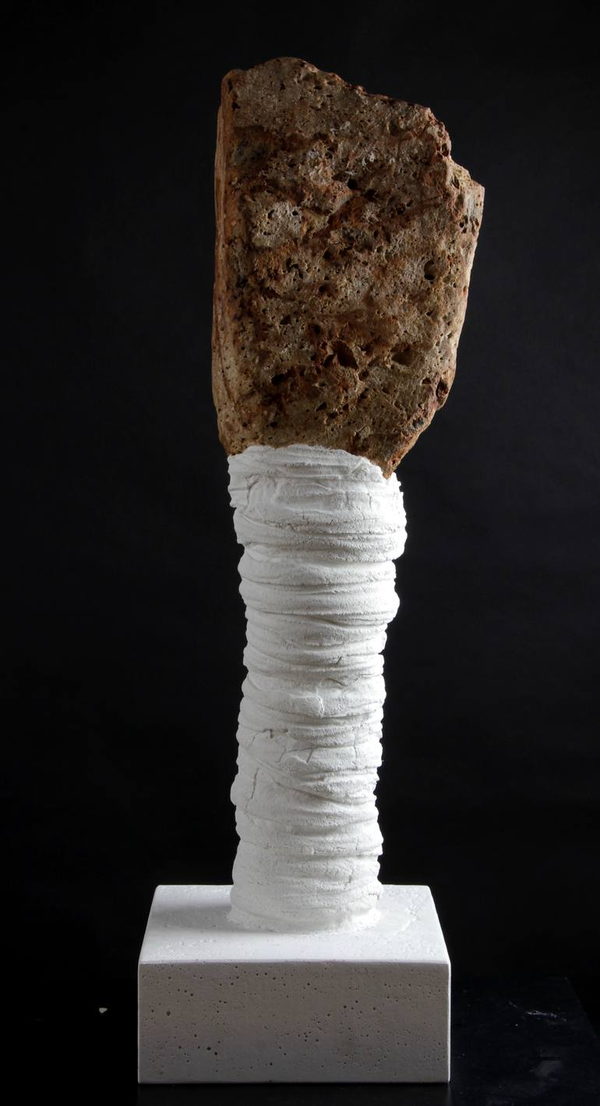 Side view of the rough stone and white wrapped column, showing the irregular stone edge above the square pale base.