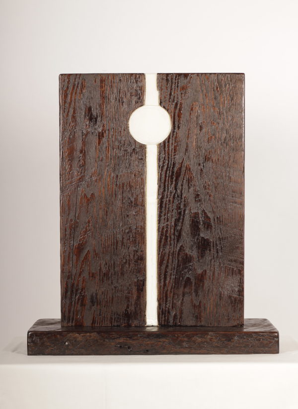 A white circular form and narrow vertical line within a dark wooden block.